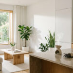 Intérieur moderne lumineux avec salon-cuisine ouvert, plantes vertes, diffuseur d'huiles essentielles et jardin visible.